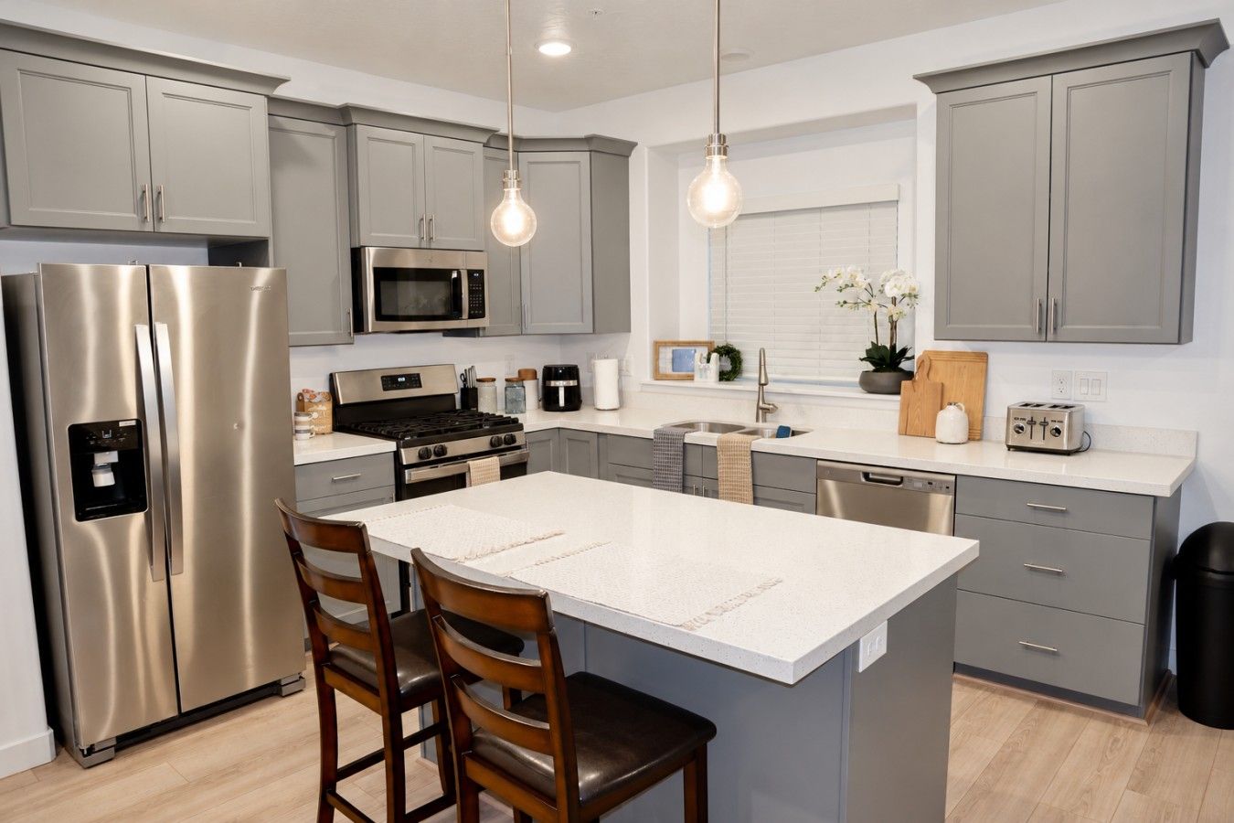 A modern kitchen with stainless steel appliances, a central island, and pendant lighting.