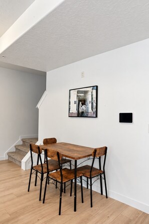 A dining area with a wooden table and chairs, a staircase, and a framed picture on the wall. - Elevated Urban Retreat | Views | Sleeps 7 + Pet (Riverton)