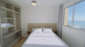 Ett välordnat hotellrum med en säng, en garderob och ett fönster med utsikt över havet.