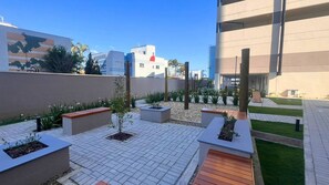 A rooftop patio with planters, seating areas, and a view of surrounding buildings. - Solarium Beach Club -Apartamento T1.1003 (Itapoá)