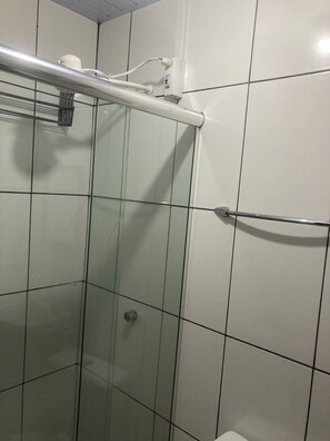 A glass-enclosed shower stall with a metal grab bar, white tiled walls, and a visible electrical outlet. - Complete apartment behind the Shopping Mall (Belém)