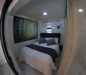Une chambre à coucher avec un lit, un grand tableau accroché au mur et une fenêtre avec des stores.