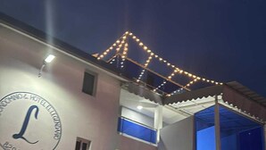 Un bâtiment avec un grand panneau lumineux en forme de « L », de nombreux balcons et une porte bleue.