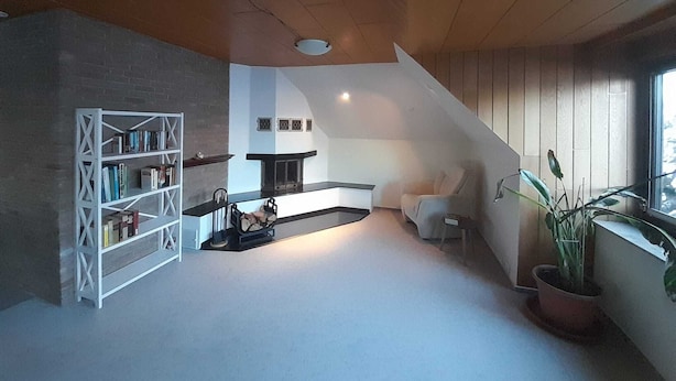 A modern living room with a fireplace, a bookshelf, a dining area, and a large window. - Spacious apartment for up to 8 people - family-friendly, pets welcome (Schneverdingen)