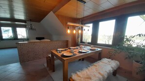 A dining area with a wooden table set for four, a bench, and a brick counter. - Spacious apartment for up to 8 people - family-friendly, pets welcome (Schneverdingen)