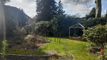 A garden with a gazebo, a stone pathway, and various plants.