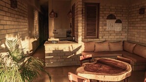Un interior acogedor con pared de ladrillo, un banco de madera y una zona de estar con cojines.