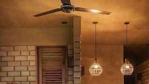Un interior acogedor con pared de ladrillo, banco de madera, mesa redonda de madera y lámparas colgantes.