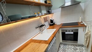 Eine moderne Küche mit Holzarbeitsplatte, Edelstahlgeräten und Fliesenboden mit Muster.