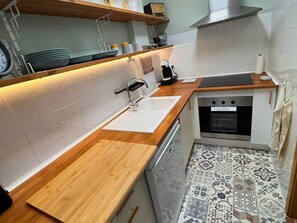 A modern kitchen with a wooden countertop, stainless steel appliances, and patterned floor tiles. - R165 Seaside Apartment (Calafell)