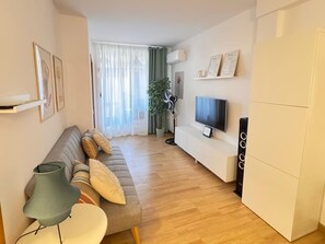 Ein modernes Wohnzimmer mit einer Couch, einem Fernseher und einer Pflanze.