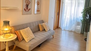 Ein Wohnzimmer mit einer Couch, einer Lampe und zwei gerahmten Bildern an der Wand.