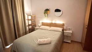 Ein ordentlich eingerichtetes Schlafzimmer mit einem Bett, Nachttischen, einem Spiegel und einer Pflanze.