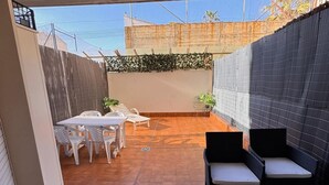 Eine Terrassenanlage mit Tisch und Stühlen, eine kleine Sitzecke und eine Zierwand.