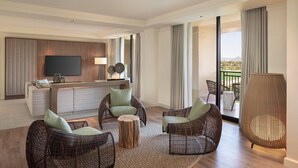 Ein modernes Hotelzimmer mit Korbmöbeln, einem Flachbildfernseher, einer Bar und großen Fenstern mit Blick.