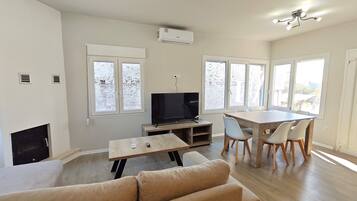 A spacious living area with a sofa, TV, dining table, and chairs.