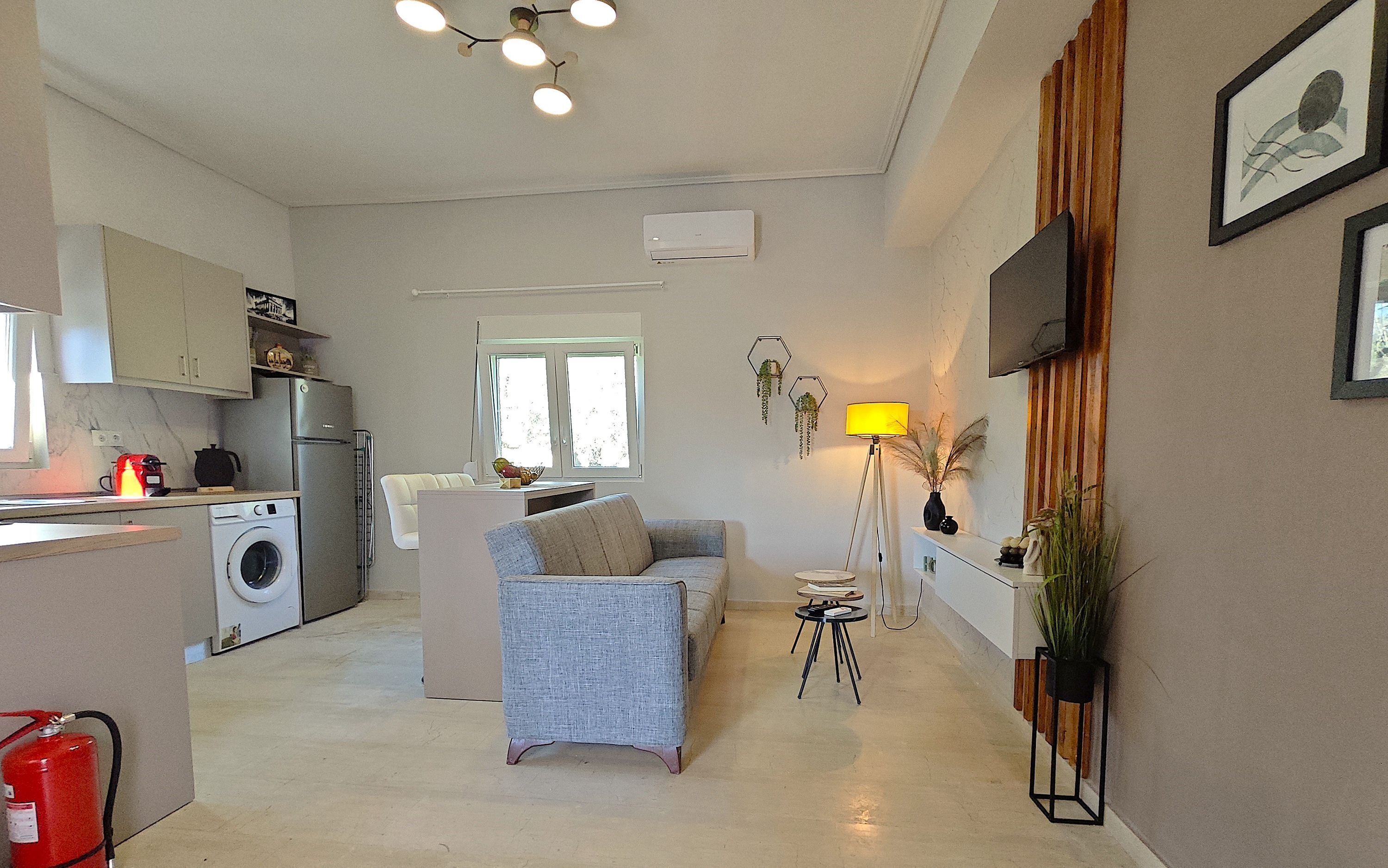 A modern kitchen with a washing machine, a dining area with a sofa, and a living room with a lamp.