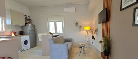 A modern kitchen with a washing machine, a dining area with a sofa, and a living room with a lamp.