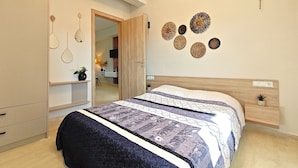 Une chambre à coucher comprenant un lit, une armoire, un miroir et des œuvres d’art décoratives au mur.