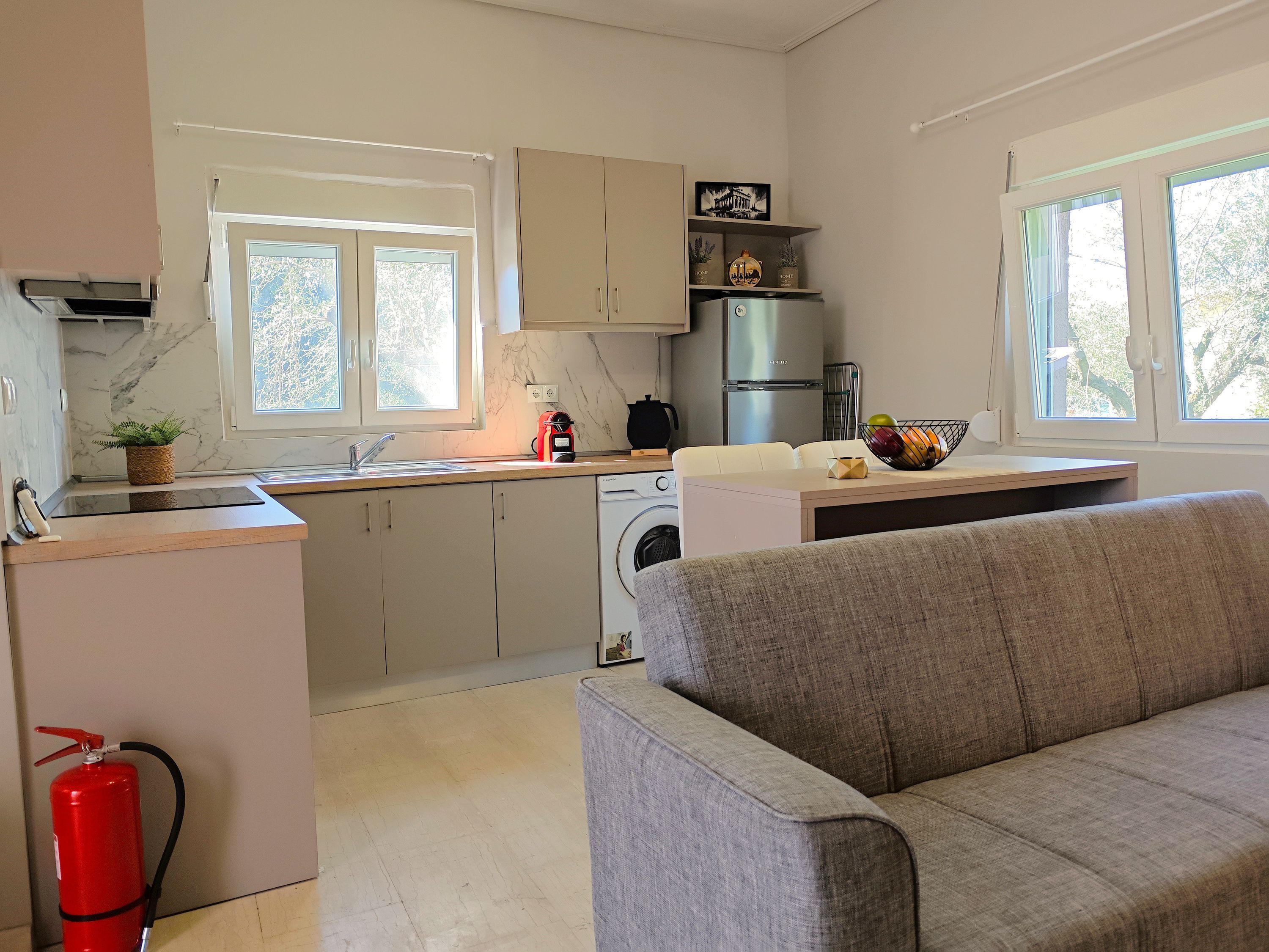 A modern kitchen with a built-in oven, a washing machine, and a dining area with a sofa.