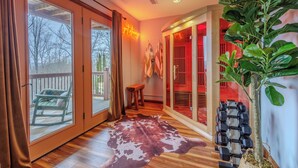 A room with large sliding glass doors, a wooden floor, a cowhide rug, a plant, and a set of dumbbells.