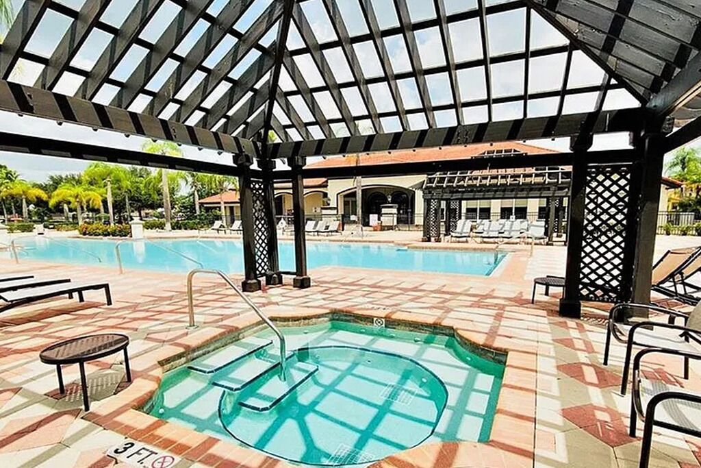 A pool area with a hot tub, lounge chairs, and a covered seating area.