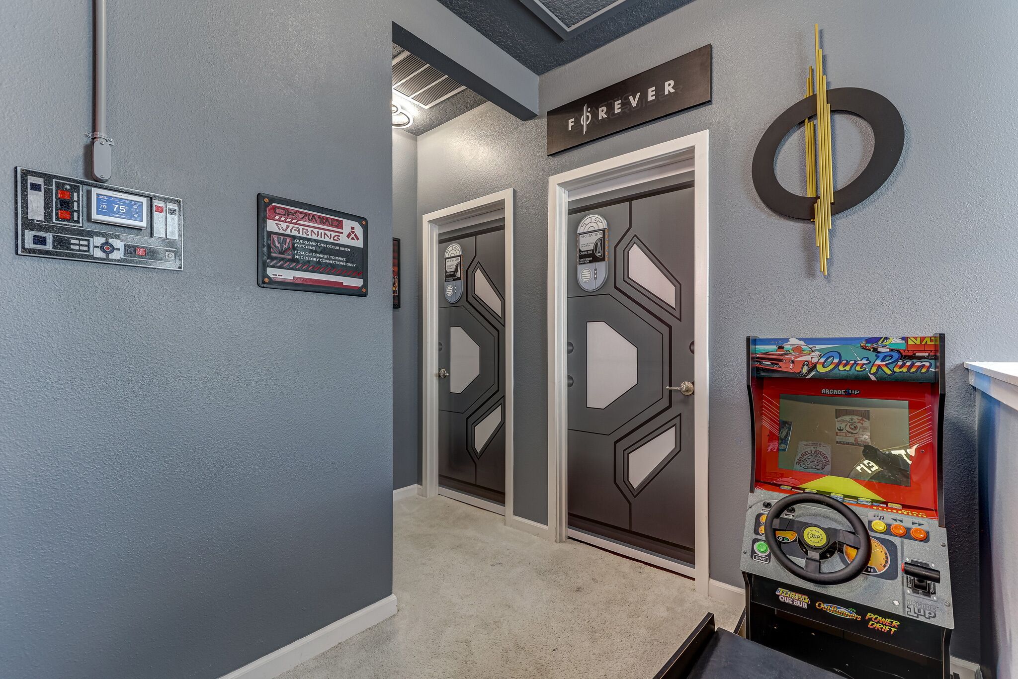 A hallway with two doors, a warning sign, a thermostat, and a game machine.