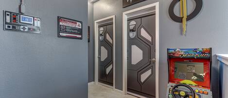 A hallway with two doors, a warning sign, a thermostat, and a game machine.
