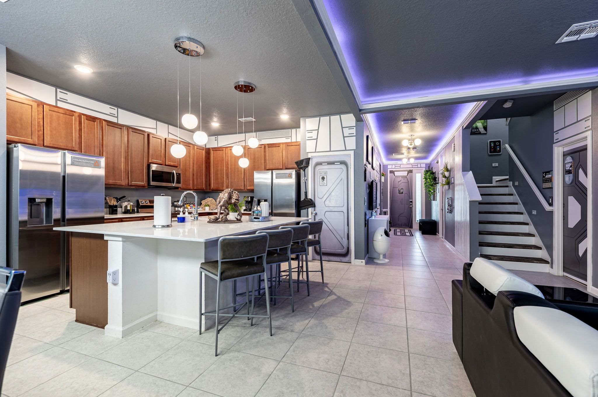 A modern kitchen with stainless steel appliances, a central island with bar stools, and pendant lighting.