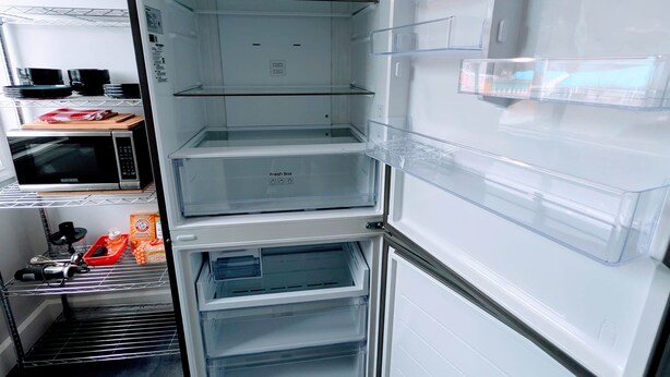 An open refrigerator with multiple shelves and a fresh box compartment. - Gordie's Lookout: Top Floor Loft Suite with Workspace (Alert Bay)