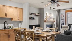 Een moderne keuken met houten kastjes, een eettafel gedekt voor vier personen, en een plafondventilator.