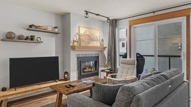 Een moderne woonkamer met een open haard, een flatscreen televisie, een bank en een salontafel.