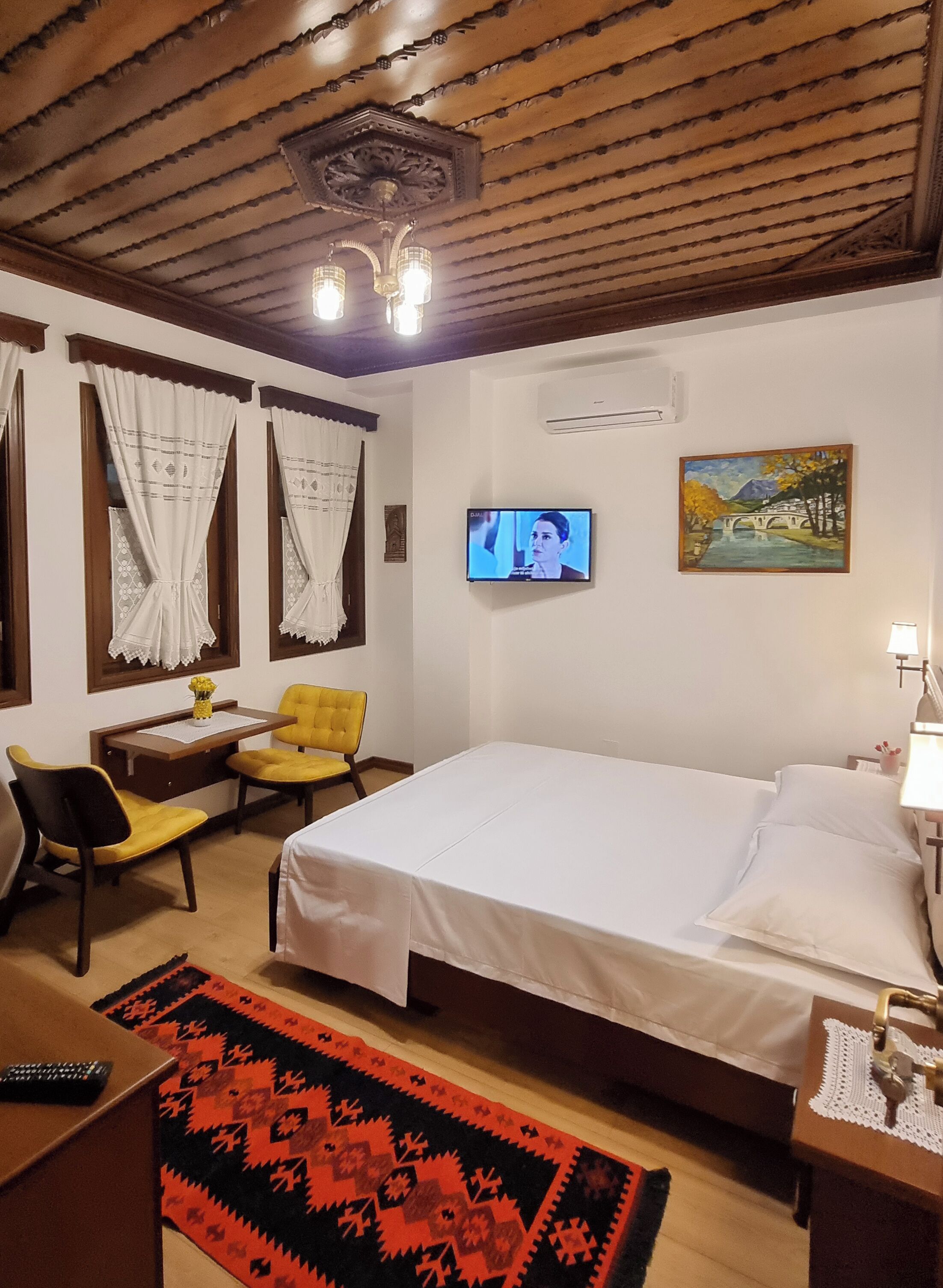 Une chambre d’hôtel avec un lit, un bureau et une chaise, une télévision et un tableau au mur.