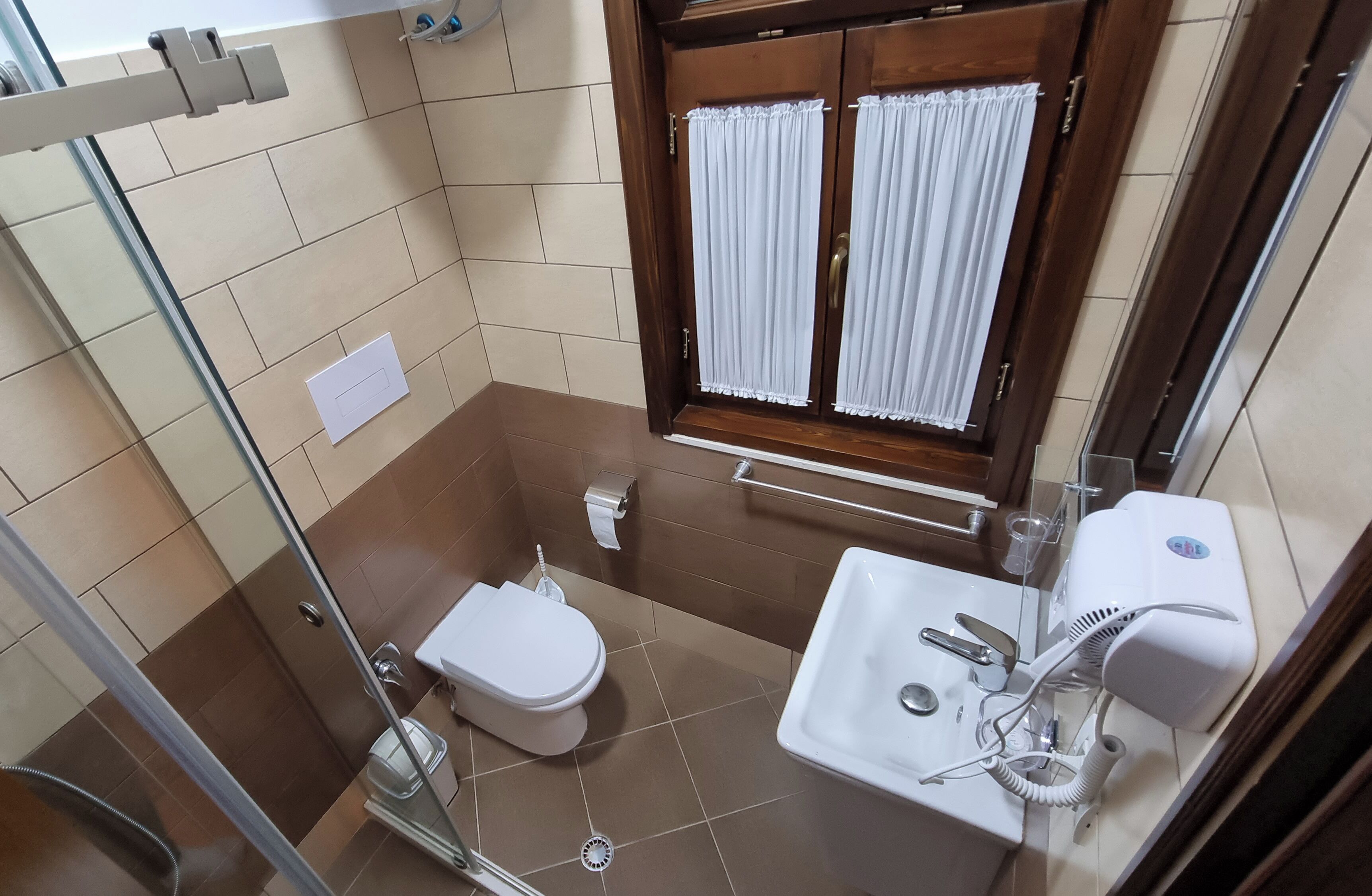 A compact bathroom with a toilet, sink, and shower.