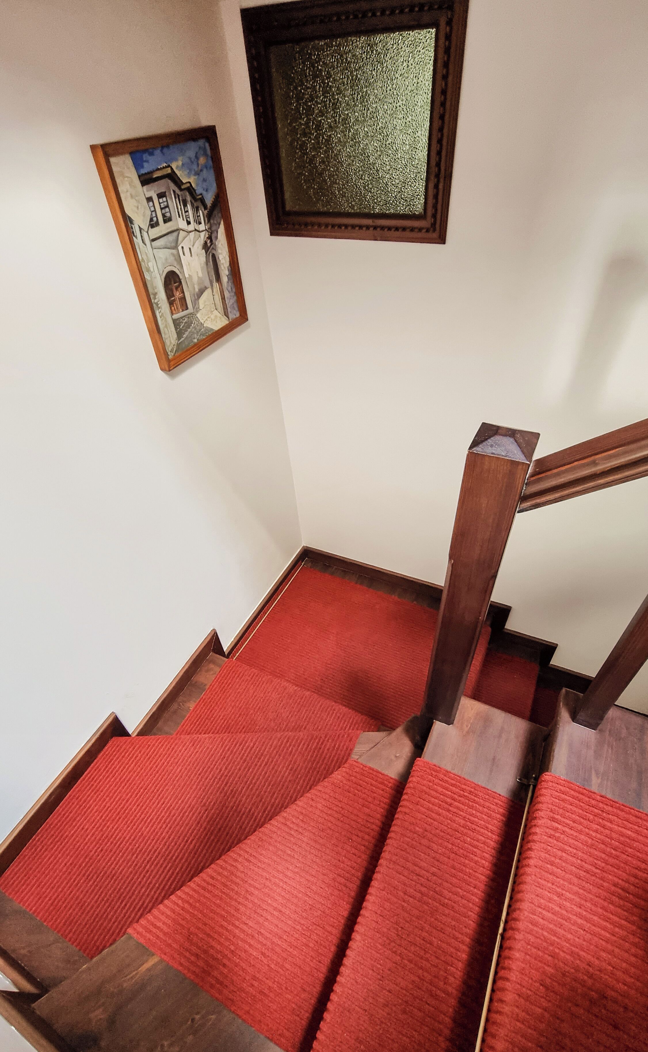 A staircase with red carpeted steps and wooden handrails.