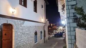 A narrow cobblestone alleyway with a white building featuring stone walls, wooden doors, and arched windows. - Master Hotel Berat (Berat)