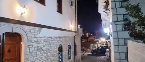 Um beco estreito de calçada com um edifício branco, com paredes de pedra, portas de madeira e janelas em arco.