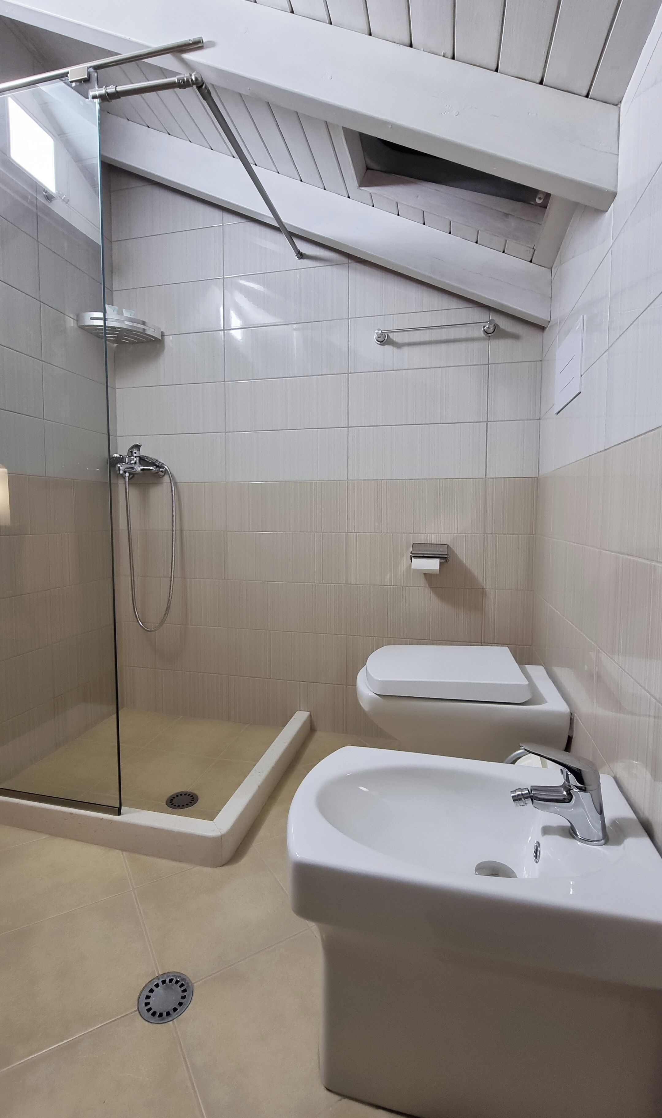 Een badkamer met een douchecabine van glas, een toilet en een wastafel met kraan.