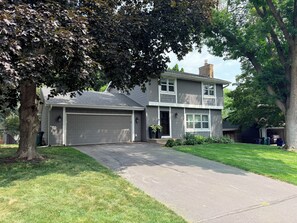 A two-story residential house with a garage, a driveway, and a well-maintained lawn.