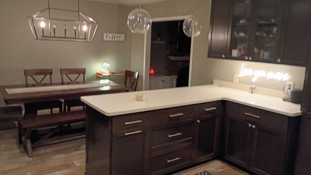 A modern kitchen with dark wood cabinets, a white countertop, and pendant lighting.