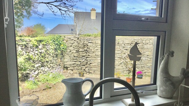 A kitchen window with a stone wall, a potted plant, and a vase. - Delightful charming townhouse in seaside Ballyvaughan awaits you (Ballyvaghan)