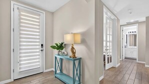 A hallway with a white door, a blue console table with a lamp, a plant, and a decorative piece. - Luxurious 2+ BR villa:highly sought after Naples Reserve for annual & seasonal (Naples)