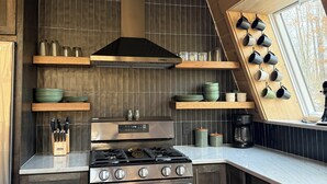 Una cocina moderna con estufa de acero inoxidable, armarios de madera y una campana extractora negra.