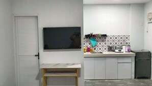 A compact kitchen with a built-in TV, a small dining table, and a microwave. - Affordable studio type guest house (Dagupan)