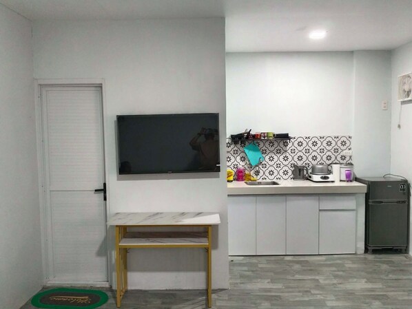 A compact kitchen with a built-in TV, a small dining table, and a microwave.