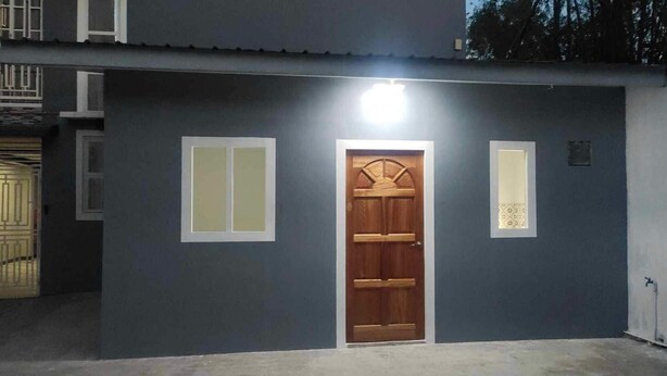 A building with a dark facade, a central wooden door, and two vertical windows on either side. - Affordable studio type guest house (Dagupan)