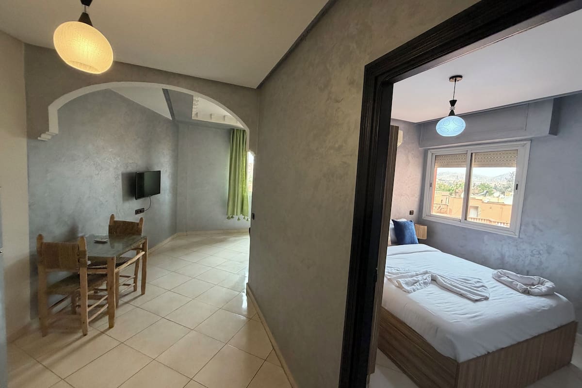 A hotel room with a bed, a desk, and a television.