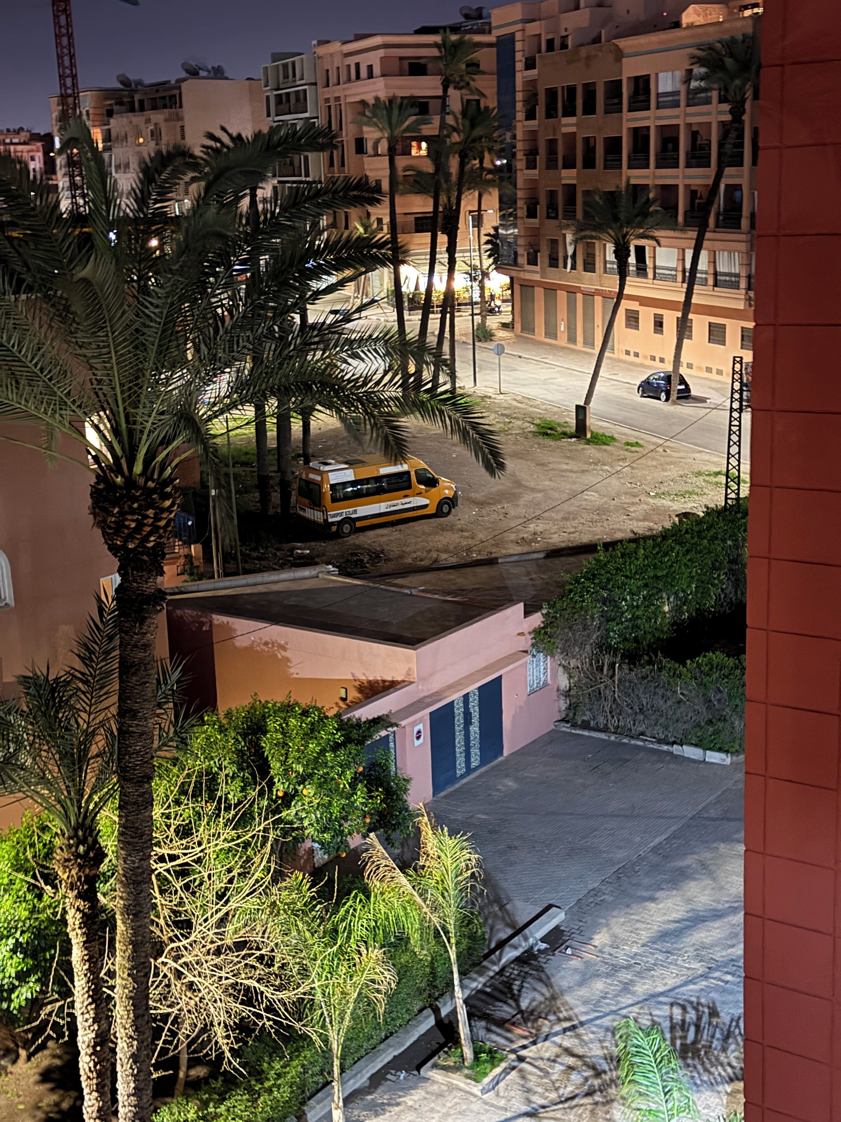 A yellow van parked on a street with palm trees and buildings in the background.