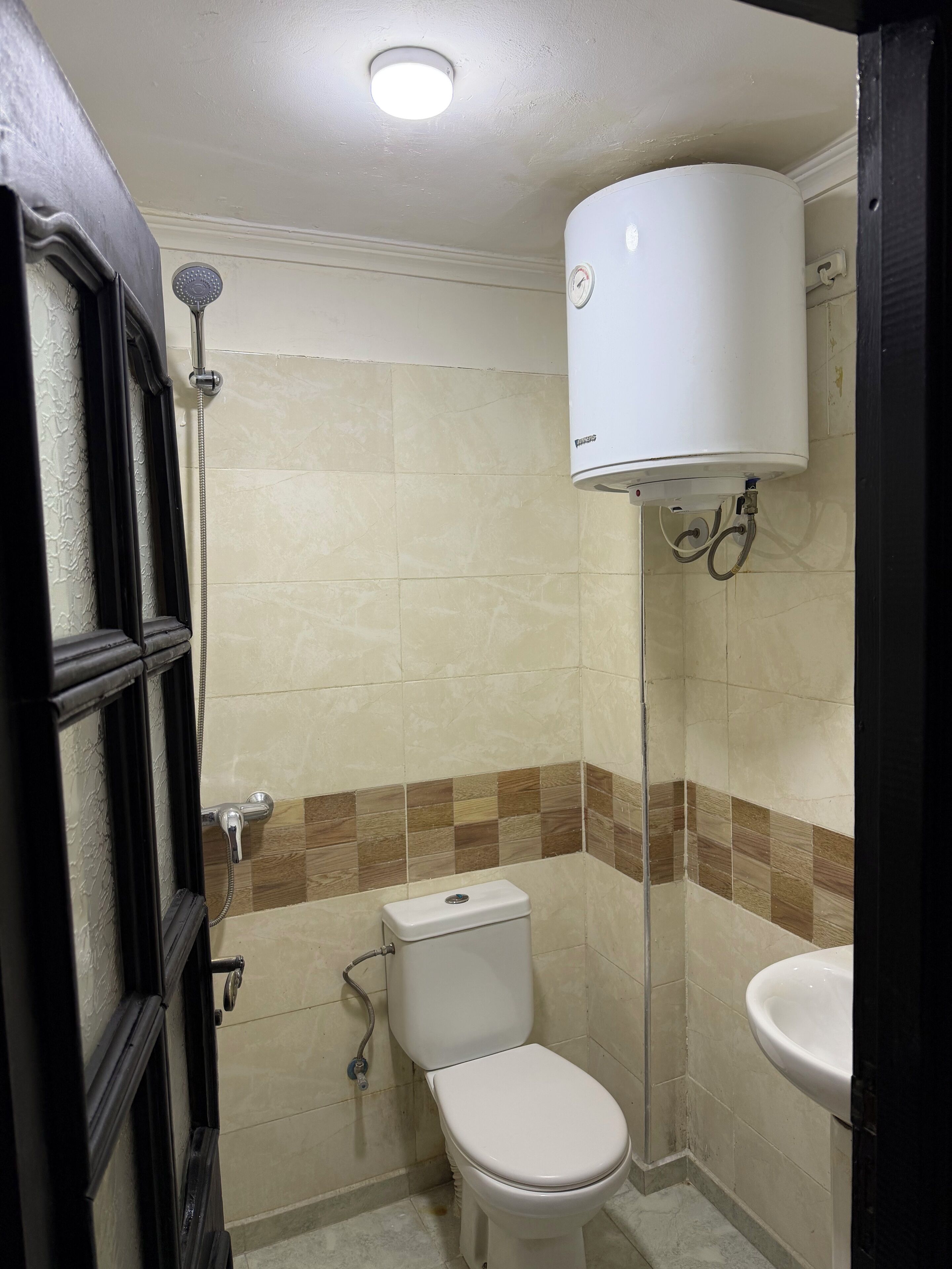 A small bathroom with a toilet, a shower, and a sink.