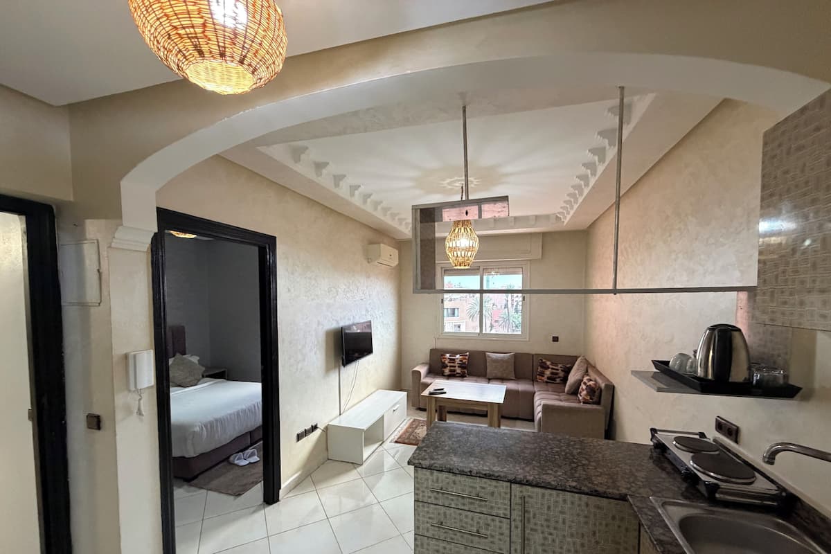 A modern kitchen with a built-in stove, a dining area with a sofa and table, and a bedroom with a bed and a TV.